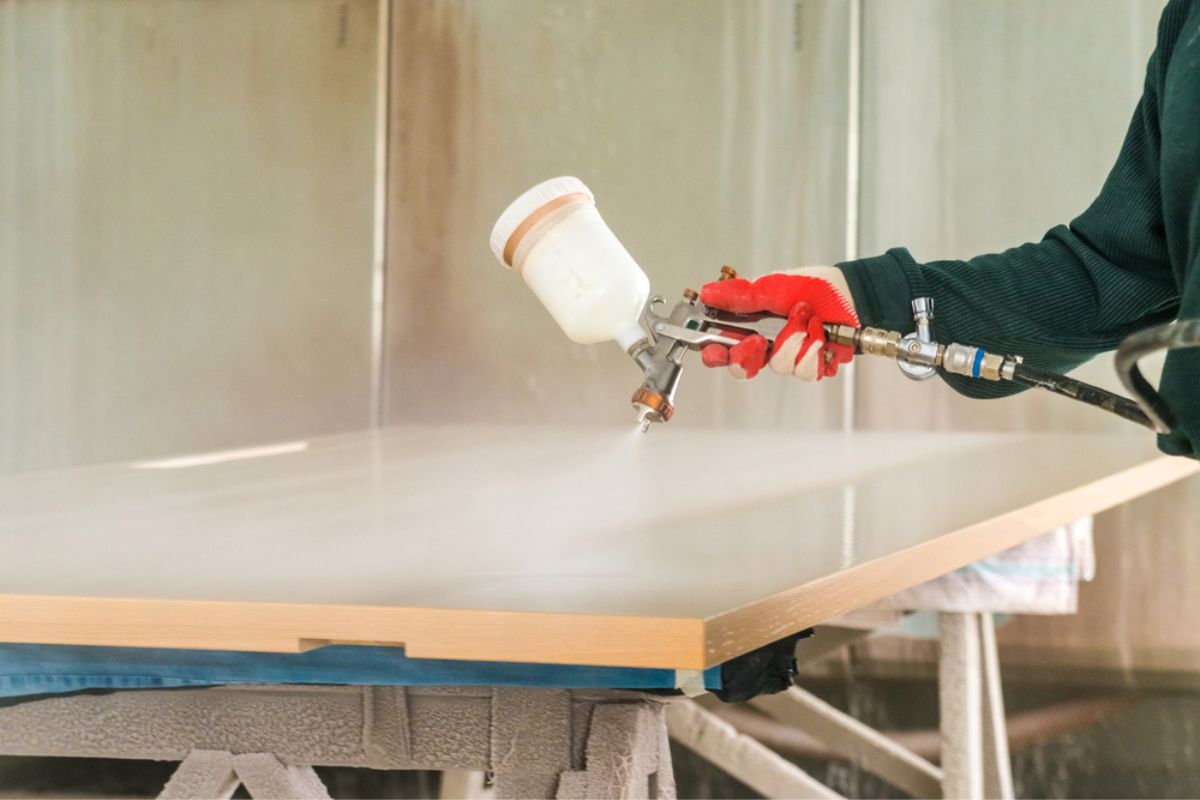 Staining wood with spray gun.