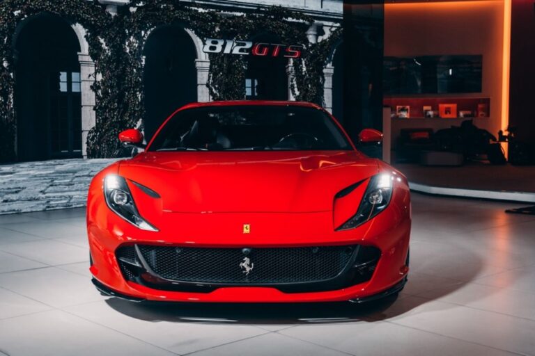 A red Ferrari 812 GTS hypercar is parked in showroom.