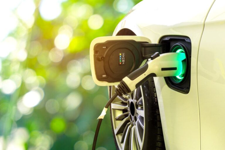 EV Car or Electric car at charging station with the power cable supply plugged in on blurred nature with soft light background.