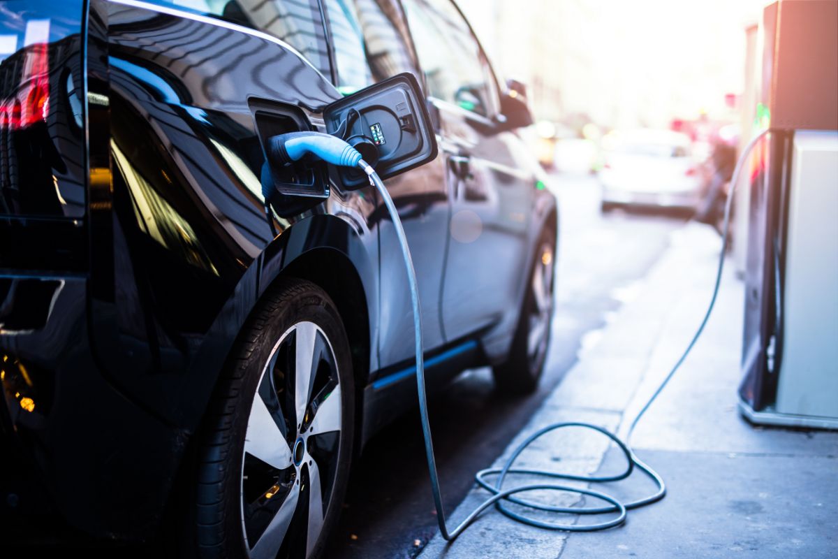 Charging modern electric car on the street using a plug.