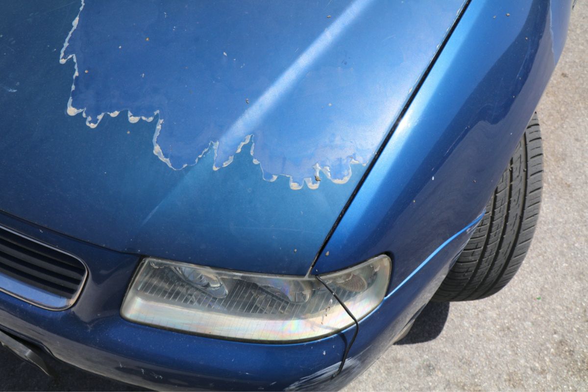 Faded car paint - peeling paint surface in a 15 year old compact blue car.