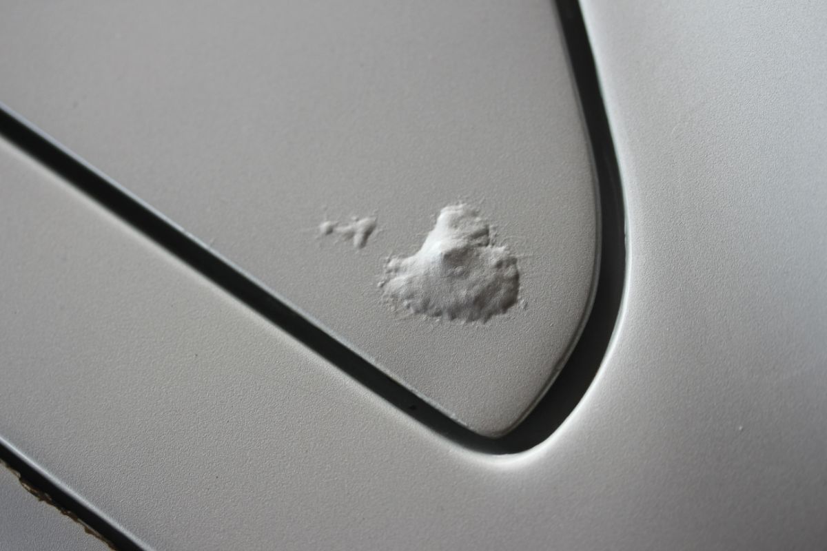 Rust bubbles on the corner of a silver car panel.