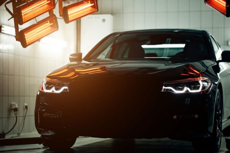 New coating of a black car with red lamps behind for drying.