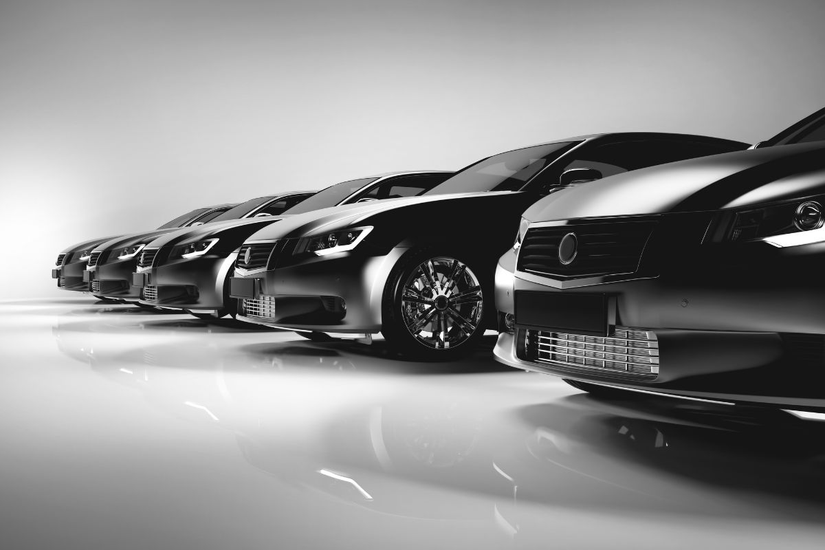 Different types of stylish cars being lined up isolated in a white and gray background.