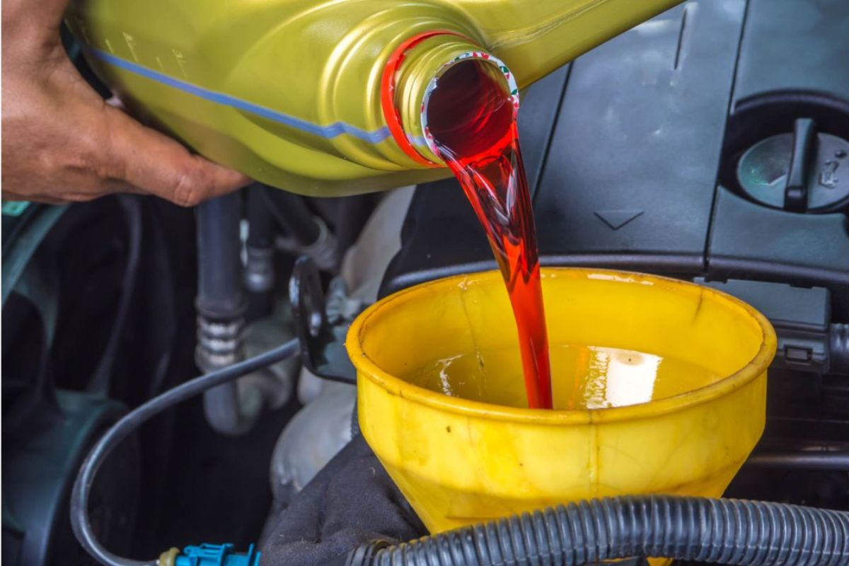 Close-up photo of a man changing his transmission fluid for his vehicle.