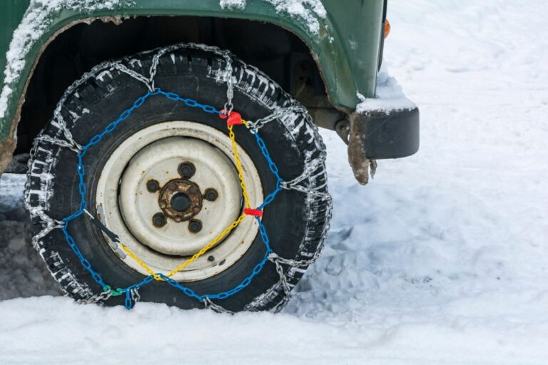 A close up photo of a diamond tire chain in a snowy terrain.