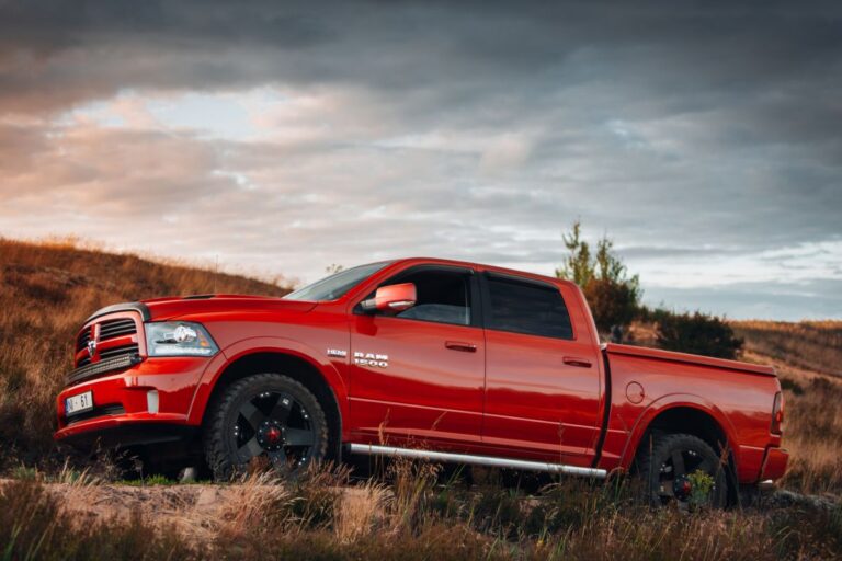 Side low angle shot of red Dodge Ram truck driving at the desert.