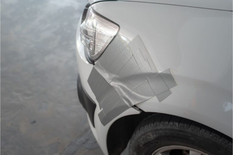 Close up photo photo of a duct taped car near the car's left headlight.