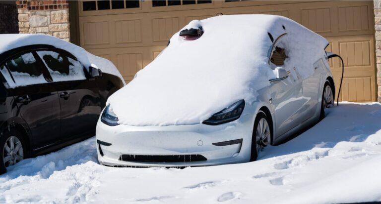 An electric vehicle covered in snow while charging.