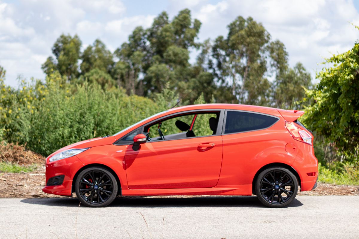 Side view angle of a Ford Fiesta an economy car in red colorway.