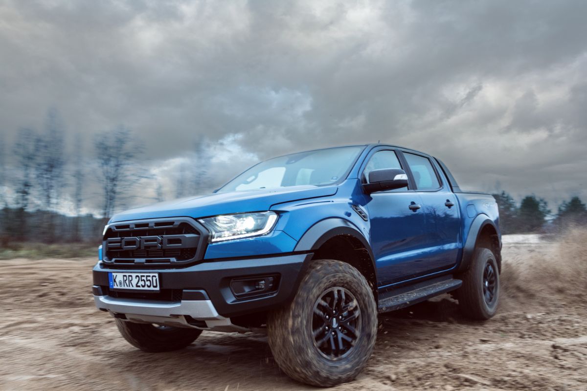 On sand and dirt, a Ford Ranger Raptor T6 mid-size pickup vehicle is seen drifting.