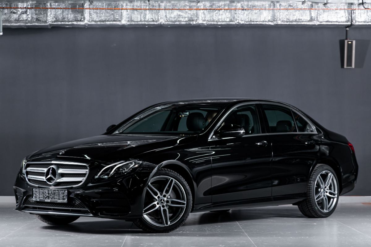 The front of a brand-new black Mercedes-Benz E-class. Photographs of a contemporary, high-end automobile parked.