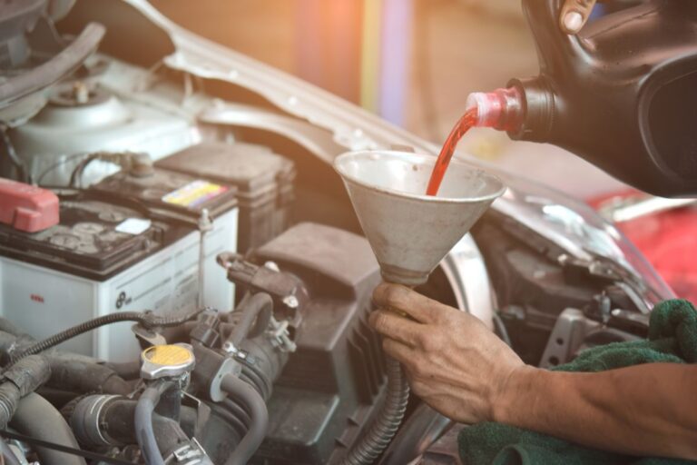 A mechanic pouring a transmission fluid in a car engine.