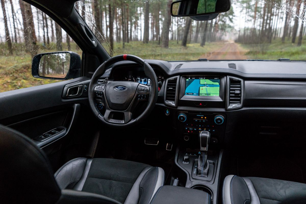 A mid-size Ford Ranger Raptor T6 pickup truck is parked on a wooded road.