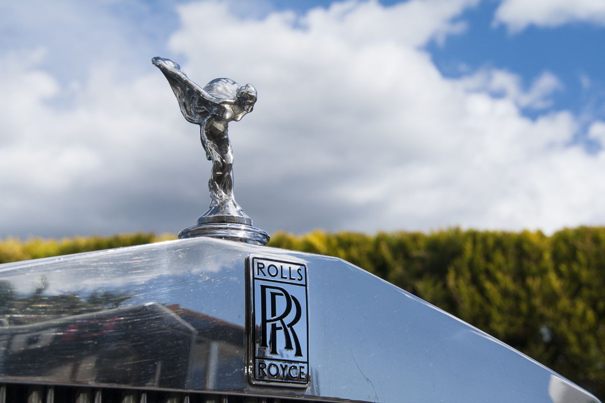 A silver rolls royce logo in the front hood of the car.