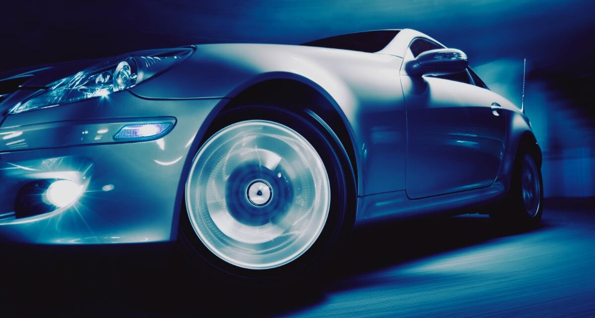 Down-side view of a metallic grey sports car in studio.