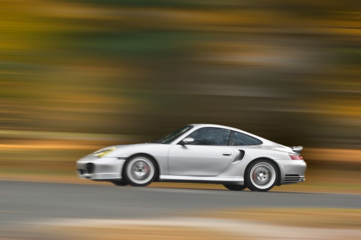 Motion photo of speeding sports car on the road with a blurry background.