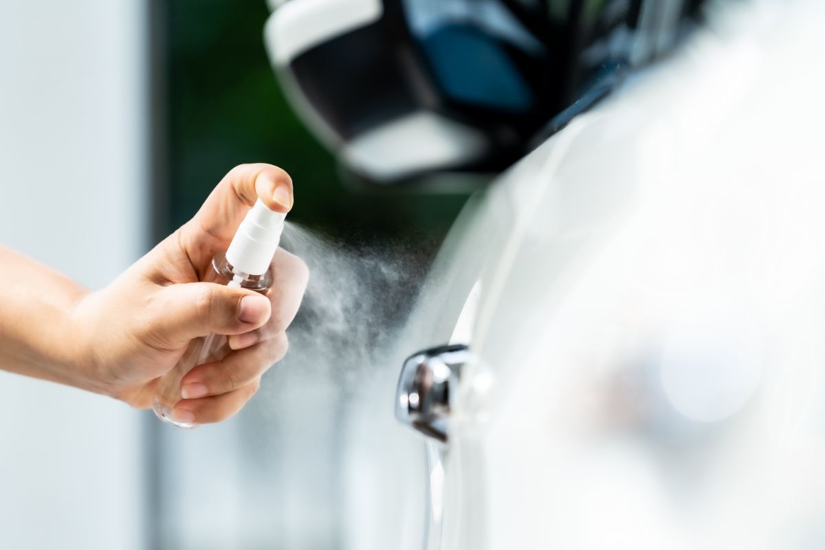 Close-up image of a white car wash cleaning using hand spraying alcohol.