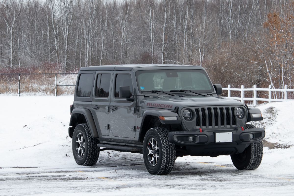 In a snowy lot, a gray Jeep Wrangler Rubicon was parked.