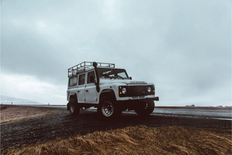 Front view of a white jeep parked at the side of the long road.