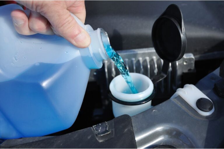 Putting fluid in a car's windshield washer.