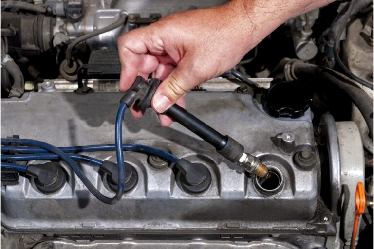 Close up photo of hand of a man installing a spark plug on his car.