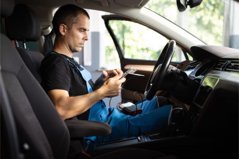 A mechanic checking an EV's onboard diagnostic using his laptop.