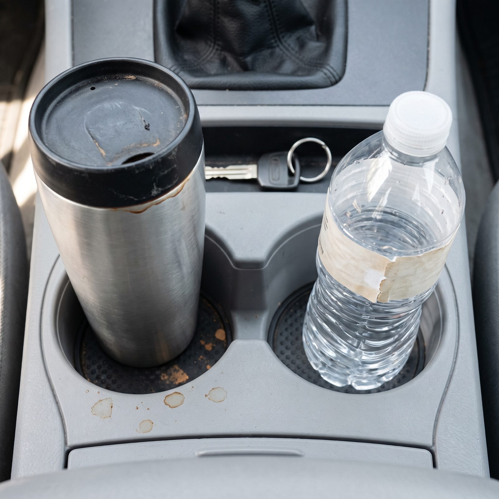 Center console cupholders holding a stainless travel mug and a half-full water bottle.